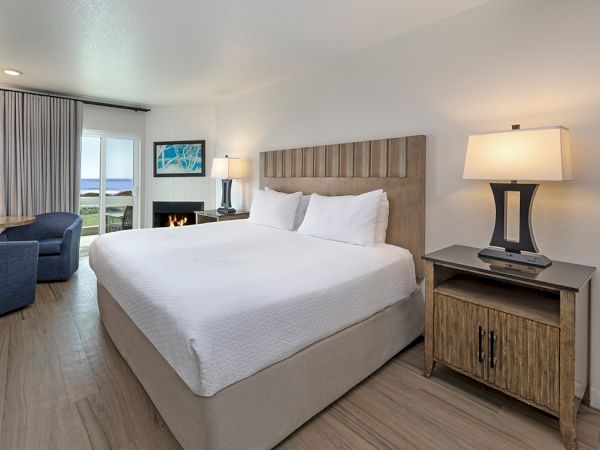 A tidy hotel room with a large bed, two nightstands, a lamp, a sofa, and a desk by the window, bright and modern.