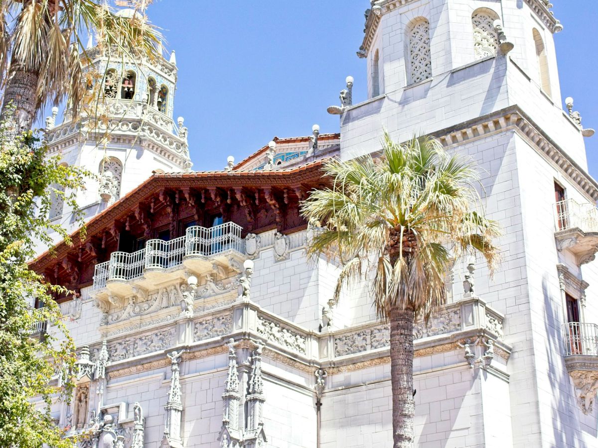 An ornate church basilica towers over the scene, framed by palm trees under a clear blue sky.